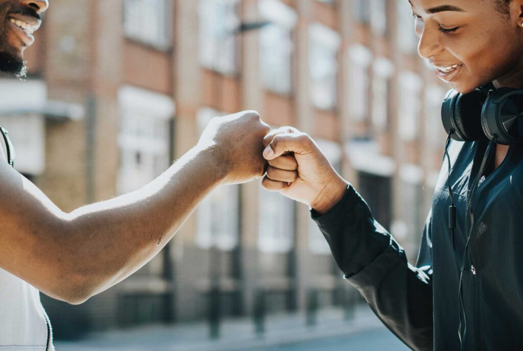 Two adults giving each other a fist bump of support