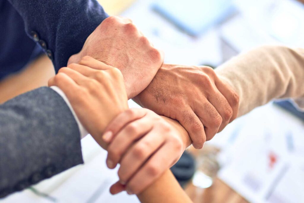 Four people coming together to support each other hands